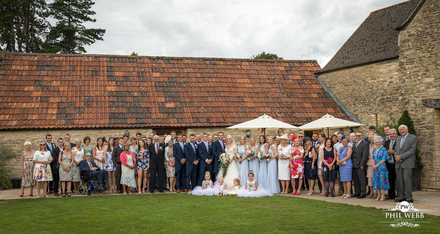 Kingscote Barn Wedding Photography bride and groom portrait with al guests