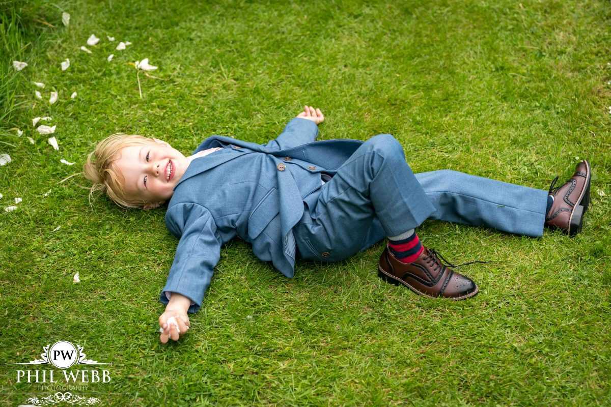 page boy lying on the grass at wedding