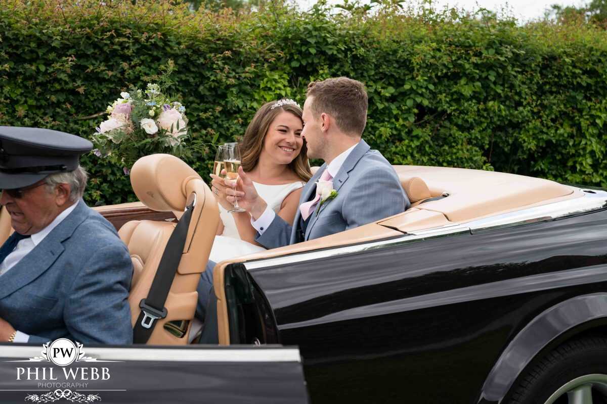 Bride and Groom drinking champagne in Bentley