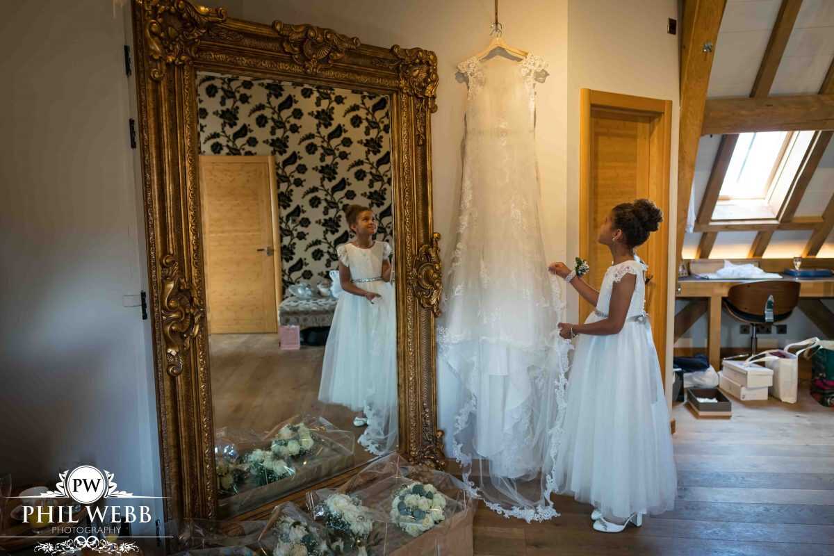 bride prep at Red House Barns Wedding Venue bridesmaid looking at wedding dress